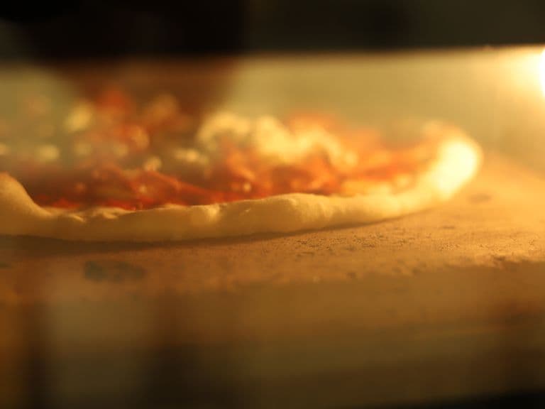 Pizza backt bei offener Flamme im Pizzaofen