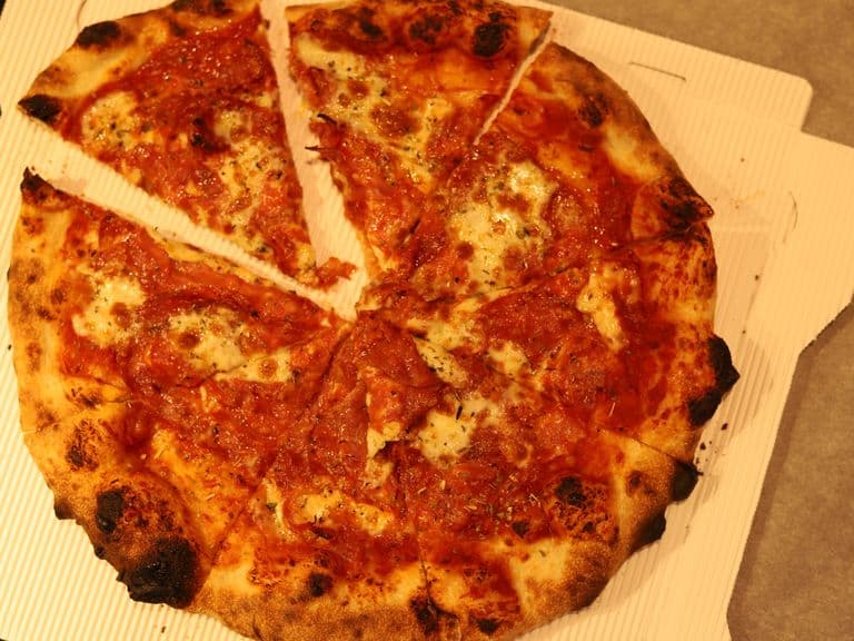 Aufgeschnittene Pizza mit Salami und geschmolzenem Käse